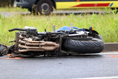 Milton motorcycle accident lawyer investigating a motorcycle laying on the road after a crash.