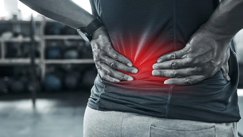 A close-up of a person in athletic wear pressing both hands against their lower back with a red highlight overlay illustrating the area of acute pain representing the kind of chronic and debilitating back injury that forms the basis of a personal injury lawsuit against a negligent party In Georgia.