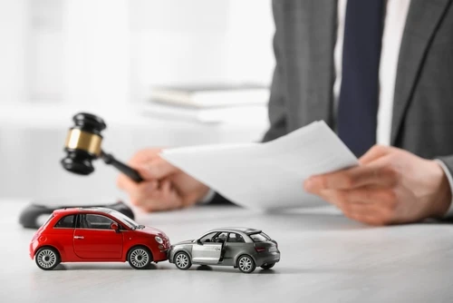 A lawyer reviews papers for the car accident claim process at a desk with toy cars.