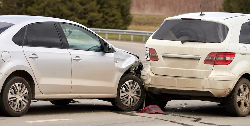 A silver sedan with a crushed front end is stopped directly behind a white SUV with rear-end damage on a roadway- depicting the type of collision that commonly leads to a car accident lawsuit when negligence is involved in Georgia.