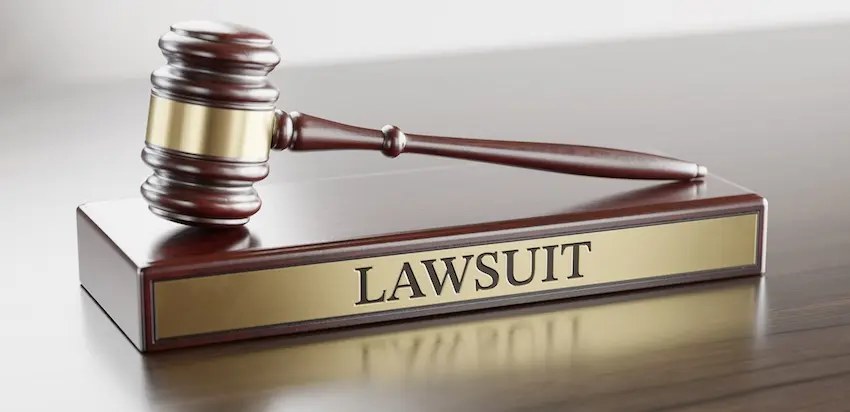 A wooden judge's gavel rests on a polished base engraved with the word "Lawsuit" on a reflective surface- serving as a direct visual representation of the formal legal process that begins when an injured victim files a car accident lawsuit with help from Ross Moore Law in Georgia.
