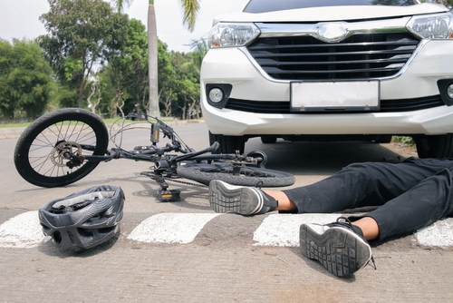 A cyclist on the ground after being hit by a car to represent a bicycle accident that a bicycle accident lawyer will have to look into.