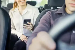 A passenger using a smartphone in the backseat of a Union City rideshare vehicle with the driver at the wheel during the trip.