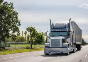 Large silver semi-truck traveling on rural highway depicting a commercial vehicle wreck risk scenario.