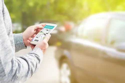 Man holding his phone showing a rideshare app after an accident where a rideshare accident lawyer is needed.