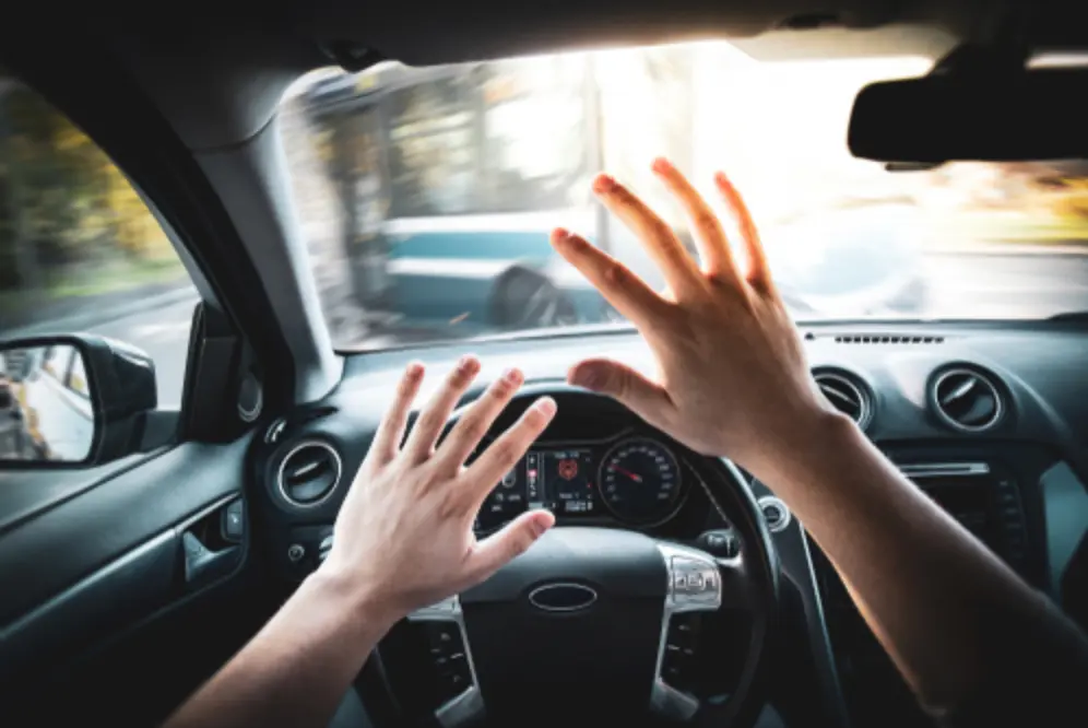 The driver's hands raised in alarm as a bus is approaching through the windshield, illustrating Marietta bus accident attorney services.