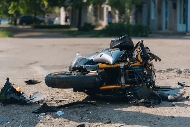 A destroyed motorcycle lying on the street with scattered parts depicts a Johns Creek motorcycle accident lawyer case scenario.